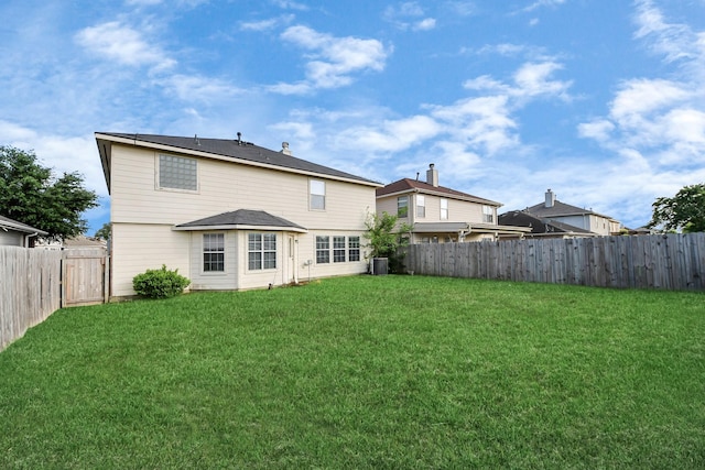 rear view of property featuring a yard, central AC, and a fenced backyard