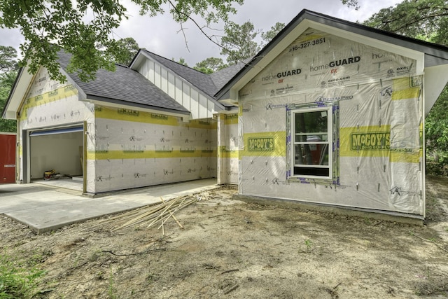 exterior space with roof with shingles and a garage