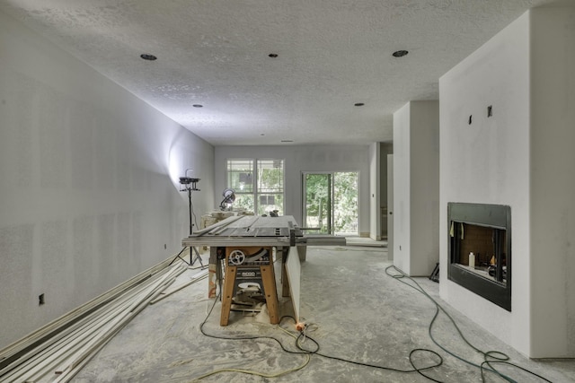 rec room featuring a textured ceiling and unfinished concrete floors