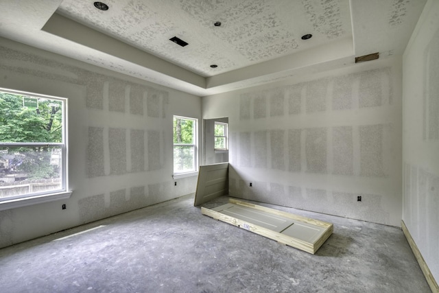 unfurnished room featuring a raised ceiling and unfinished concrete flooring