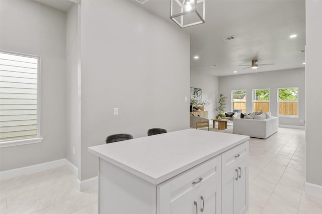 kitchen with light countertops, a kitchen island, recessed lighting, and white cabinetry