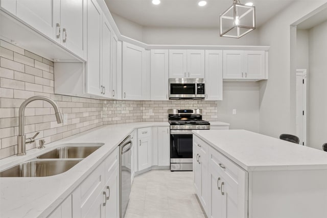 kitchen featuring white cabinets, a sink, a center island, stainless steel appliances, and recessed lighting