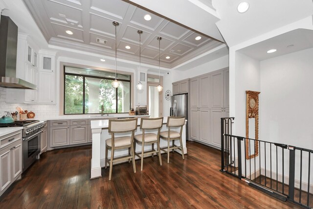 403 W Pierce St W, Houston, TX 77019 - kitchen with stainless steel appliances, wall chimney exhaust hood, dark wood-style floors, a center island, and coffered ceiling