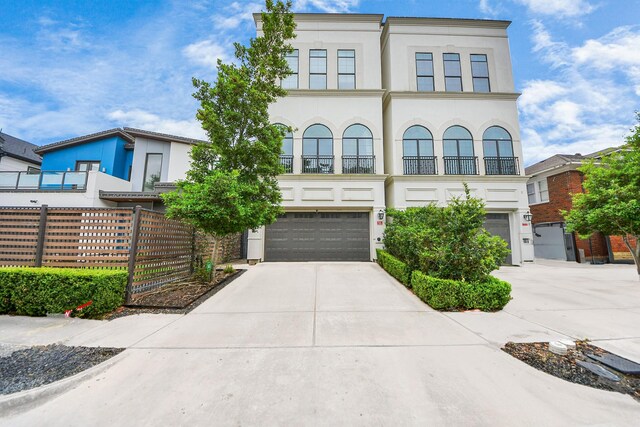 403 W Pierce St W, Houston, TX 77019 - view of front facade with a garage, concrete driveway, stucco siding, fence, and a balcony