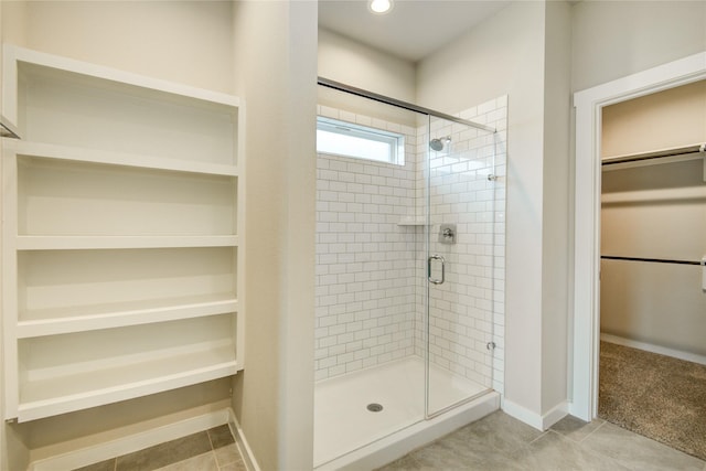 bathroom with baseboards, tile patterned floors, a spacious closet, and a shower stall