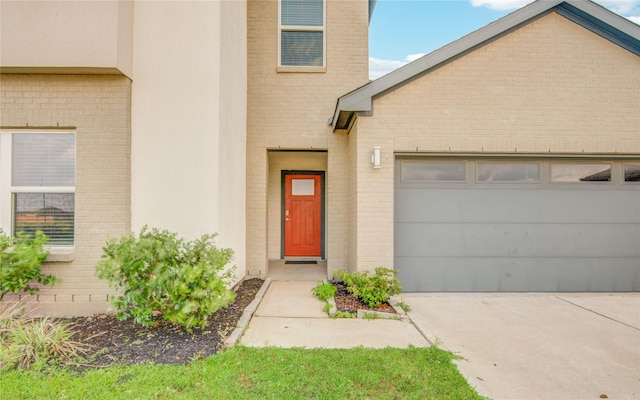 doorway to property with concrete driveway, brick siding, and an attached garage