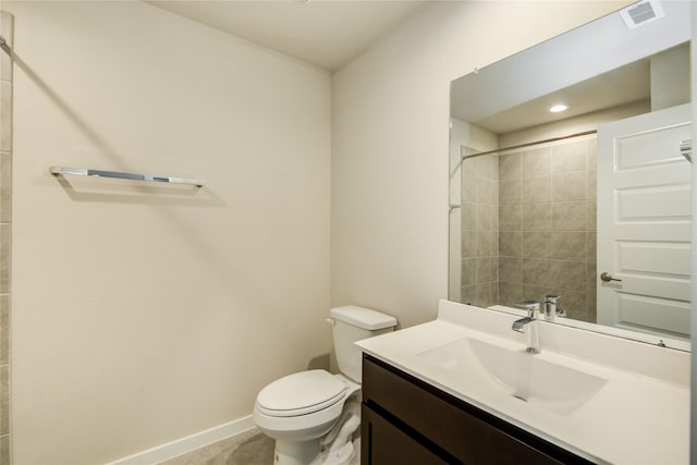 bathroom with visible vents, vanity, toilet, baseboards, and a tile shower
