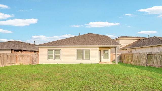 rear view of property with a fenced backyard, a yard, and roof with shingles