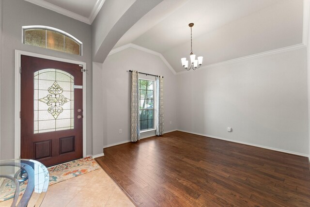 foyer entrance featuring an inviting chandelier, crown molding, wood finished floors, baseboards, and vaulted ceiling