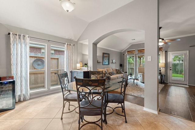 dining area featuring arched walkways, a ceiling fan, light tile patterned floors, lofted ceiling, and ornamental molding