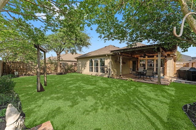 back of house with ceiling fan, roof with shingles, a lawn, a fenced backyard, and a patio