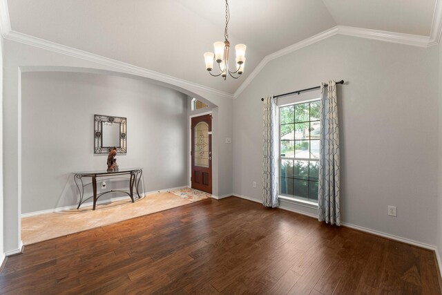 entryway featuring an inviting chandelier, ornamental molding, wood finished floors, lofted ceiling, and arched walkways