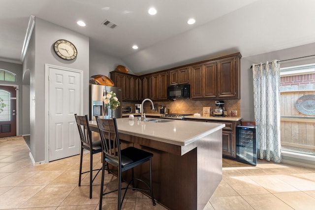 kitchen with visible vents, black microwave, stainless steel fridge, a sink, and backsplash