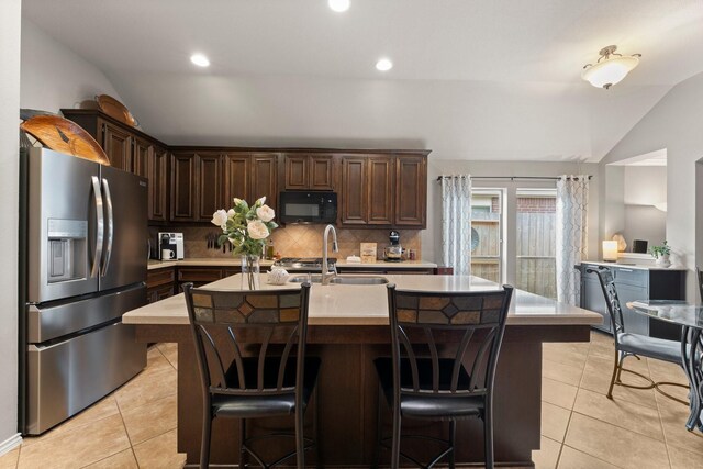kitchen with light countertops, stainless steel refrigerator with ice dispenser, black microwave, and vaulted ceiling