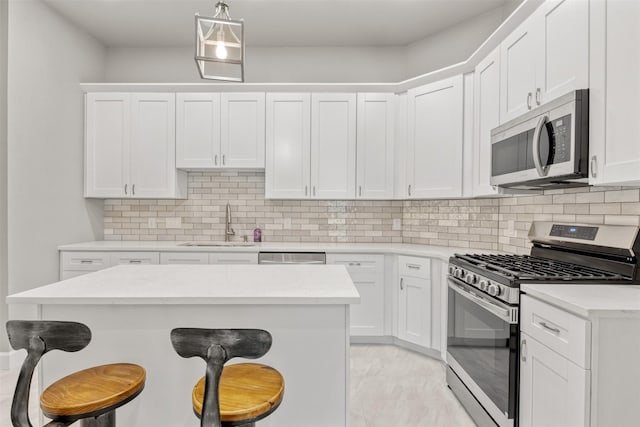 8161 Crestview Dr, Houston, TX 77028 - kitchen featuring appliances with stainless steel finishes, a sink, a breakfast bar area, decorative backsplash, and white cabinetry
