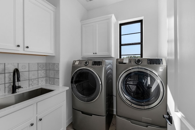 clothes washing area with cabinet space, tile patterned floors, a sink, and washing machine and clothes dryer