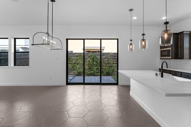 unfurnished dining area featuring plenty of natural light, recessed lighting, baseboards, and a sink
