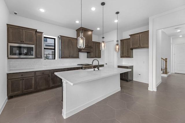 kitchen featuring light countertops, appliances with stainless steel finishes, decorative backsplash, and a sink