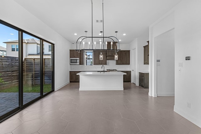 kitchen with dark brown cabinets, stainless steel microwave, a sink, and a healthy amount of sunlight
