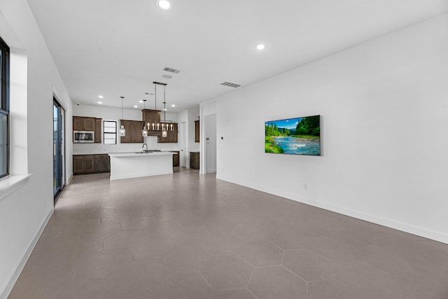 unfurnished living room featuring recessed lighting, baseboards, visible vents, and a sink