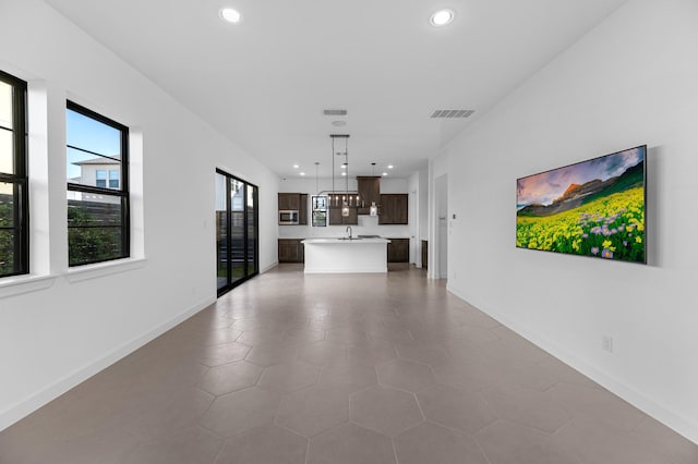 unfurnished living room featuring baseboards, recessed lighting, and visible vents