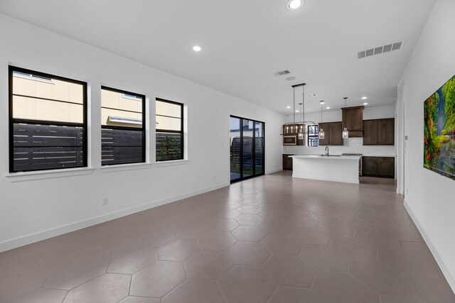 unfurnished living room featuring visible vents, recessed lighting, baseboards, and a sink
