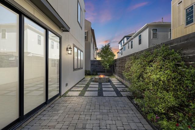 property exterior at dusk with a fire pit, a fenced backyard, and a patio area