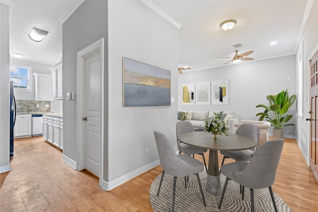 dining space featuring crown molding, baseboards, ceiling fan, and light wood-type flooring