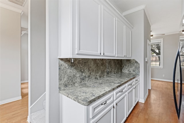 interior space with crown molding, decorative backsplash, visible vents, and light wood-type flooring