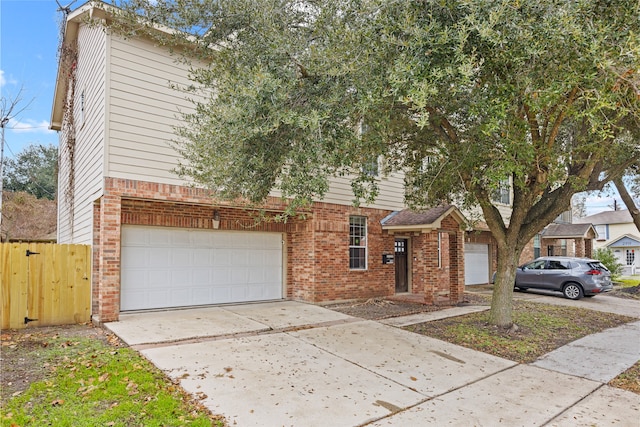 view of property hidden behind natural elements with brick siding, driveway, fence, and a garage