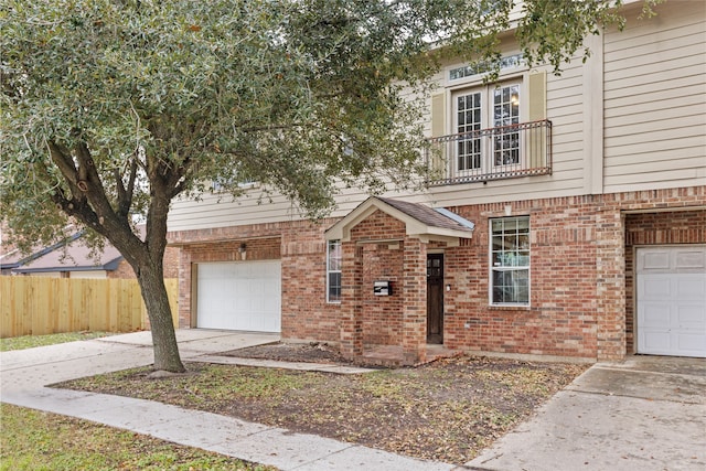 view of front facade featuring fence, brick siding, a garage, a balcony, and driveway