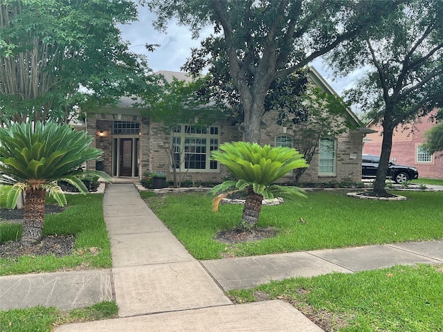 obstructed view of property featuring a front yard and brick siding