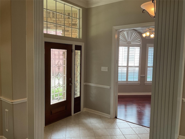 foyer entrance featuring light tile patterned floors, baseboards, decorative columns, and a ceiling fan