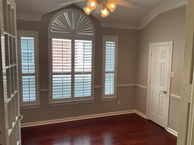 empty room with a ceiling fan, dark wood finished floors, a wealth of natural light, and ornamental molding