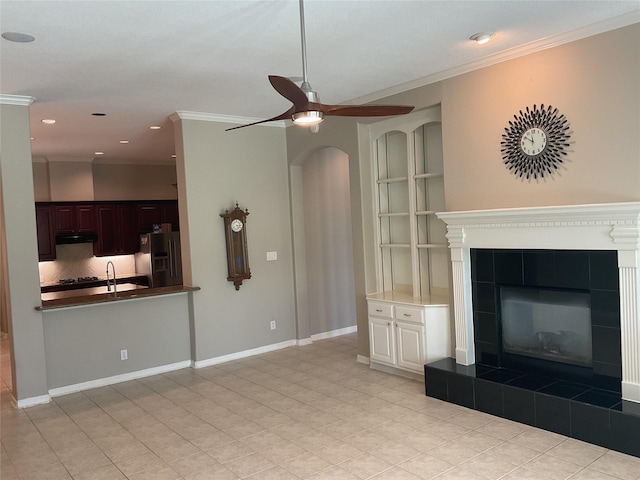 unfurnished living room with ceiling fan, a tiled fireplace, recessed lighting, light tile patterned floors, and ornamental molding