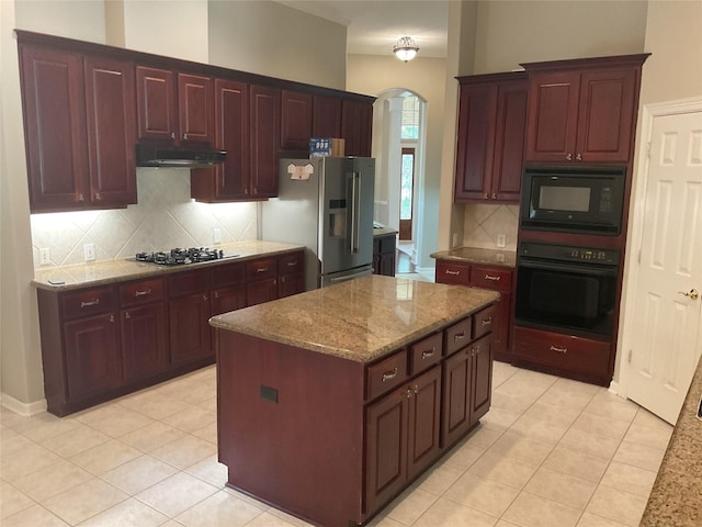 kitchen with backsplash, arched walkways, dark brown cabinets, black appliances, and light tile patterned flooring