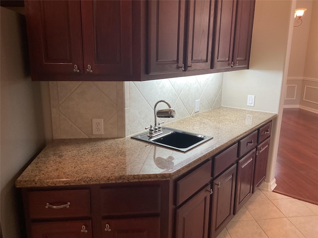 kitchen with a sink, tasteful backsplash, and light wood-type flooring