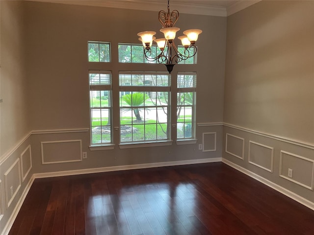 spare room with crown molding, a decorative wall, a chandelier, dark wood finished floors, and a wainscoted wall