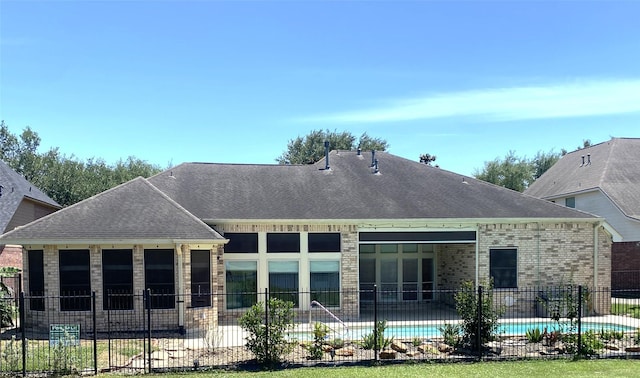back of house featuring fence, roof with shingles, a fenced in pool, brick siding, and a patio area
