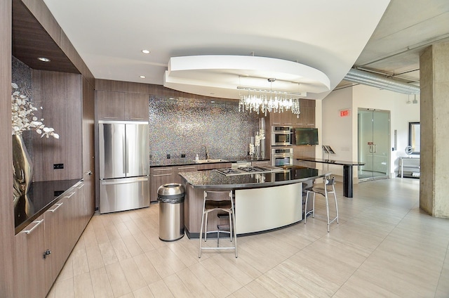 kitchen featuring appliances with stainless steel finishes, a sink, a breakfast bar area, tasteful backsplash, and modern cabinets