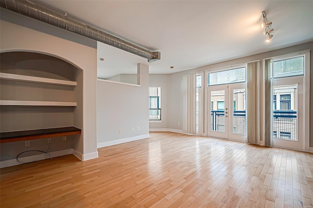unfurnished room with baseboards, rail lighting, light wood-style flooring, and french doors