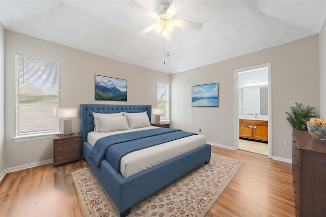 bedroom with baseboards, ensuite bathroom, ceiling fan, light wood-type flooring, and a sink