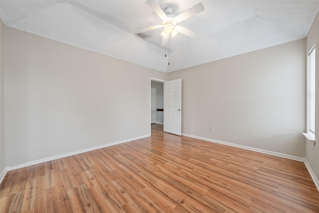 spare room with ceiling fan, visible vents, baseboards, and light wood-type flooring