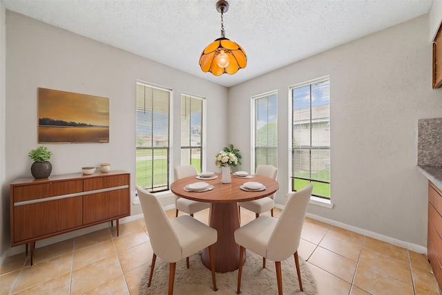 dining room featuring baseboards, a textured ceiling, and light tile patterned floors
