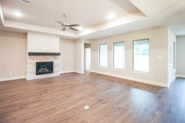 unfurnished living room with visible vents, a ceiling fan, a raised ceiling, and wood finished floors