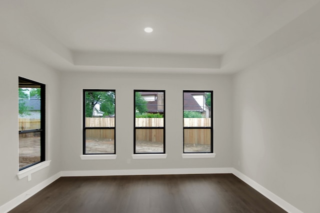 spare room featuring recessed lighting, a tray ceiling, dark wood-style floors, and baseboards