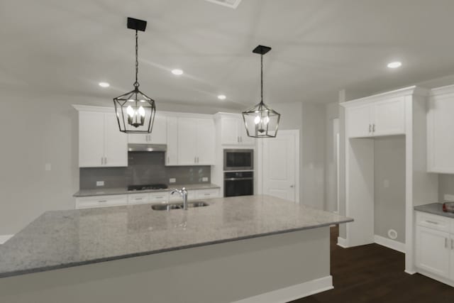 kitchen featuring recessed lighting, white cabinetry, stainless steel microwave, under cabinet range hood, and a sink