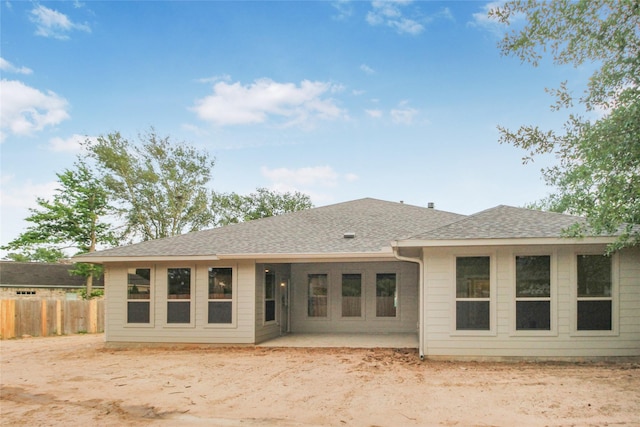 rear view of house with a patio, a shingled roof, and fence
