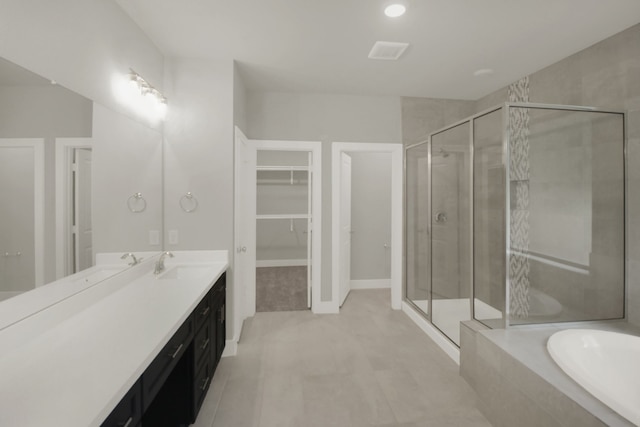 bathroom with vanity, a bath, a stall shower, and a spacious closet