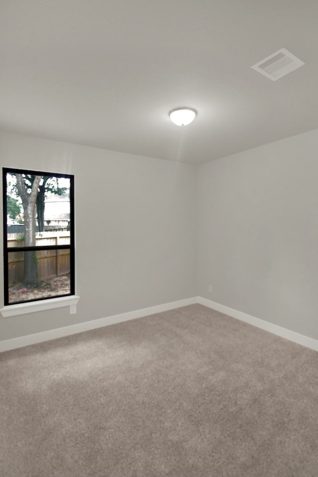 carpeted spare room featuring baseboards and visible vents